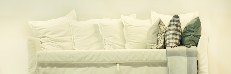 white sofa with white and colored pillows against the white wall ,concept elements interior objects Banner