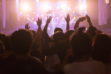 Fototapeta na wymiar Crowd at concert and blurred stage lights, noise added later in post processing for vintage usage