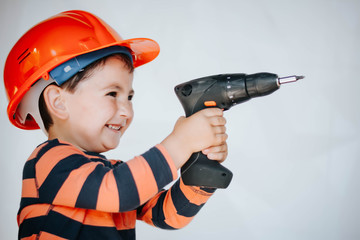 little builder in the helmet with a drill and saw the work of thinking about the future