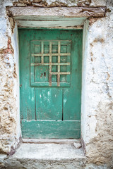 Front door. Old turquoise wooden door with bars and eroded stone wall. Entrance to the house