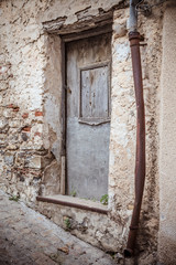  Front door. Old wooden and metal door, rusty pipe and eroded stone wall