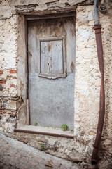 Front door. Old wooden and metal door, rusty pipe and eroded stone wall