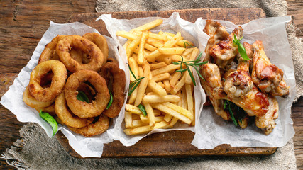 Fast food snacks - onion rings, fries and chicken wings