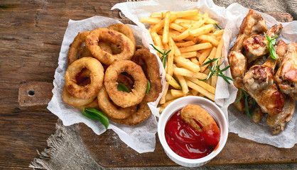 Fast food snacks - onion rings, fries and chicken wings