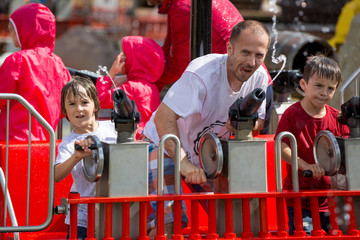 People enjoying water attraction in a fun fair park. Family fun on holidays