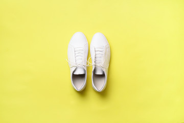 Stylish white sneakers and rope on yellow background with copy space. Top view. Minimal flat lay. Summer shoes collection. First step concept