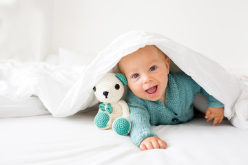 Little cute baby boy, child in knitted sweater, holding knitted toy, smiling happily at camera © Tomsickova