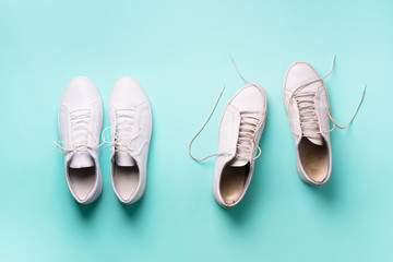 Old dirty sneakers vs new white sneakers on blue background. Trendy footwear. Top view. Concept of experience, discipline and chaos, accuracy \ mess, stylish shoes. Back to school