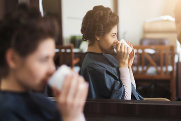Young brunette having cup of coffee at the beauty salon