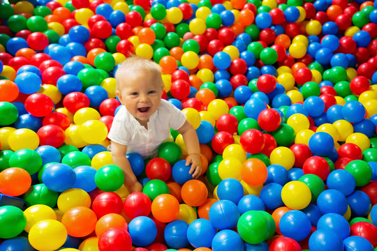 Cute toddler boy, child, playing in colorful balls in children playground