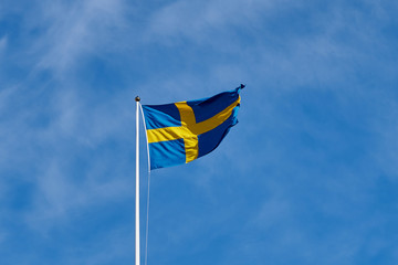 Flag of Sweden against a blue cloudy sky on a background. 