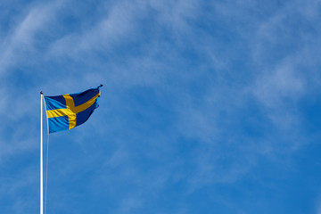 Flag of Sweden against a blue cloudy sky on a background. Copy space for text.