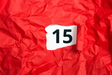 rotes zerknülltes Papier, aufgerollt mit Zahl fünfzehn - 15 auf weißem Untergrund