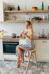 Photo of beautiful woman in long striped dress in kitchen