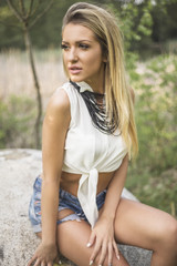 Outdoor portrait of beauty blond woman wearing blue jeans shorts and white t-shirt at daytime