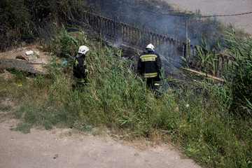 Firemen in helmets extinguish the fire