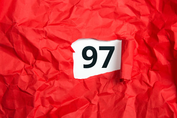 rotes zerknülltes Papier, aufgerollt mit Zahl siebenundneunzig - 97 auf weißem Untergrund