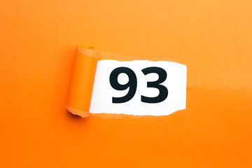 Zahl dreiundneunzig - 93 verdeckt unter aufgerissenem orangen Papier