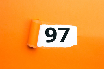Zahl siebenundneunzig - 97 verdeckt unter aufgerissenem orangen Papier