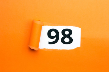 Zahl achtundneunzig - 98 verdeckt unter aufgerissenem orangen Papier