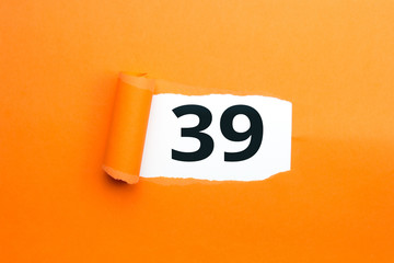 Zahl neununddreißig - 39 verdeckt unter aufgerissenem orangen Papier