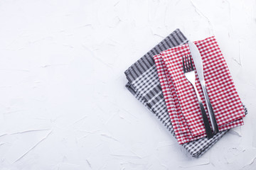 Fototapeta na wymiar Table towels of red and gray color, fork and knife. White table. Servlet for lunch. Copy space.