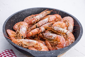 Large shrimps fried in a frying pan. On a white table. Lunch from seafood. Free space for text. Copy space,