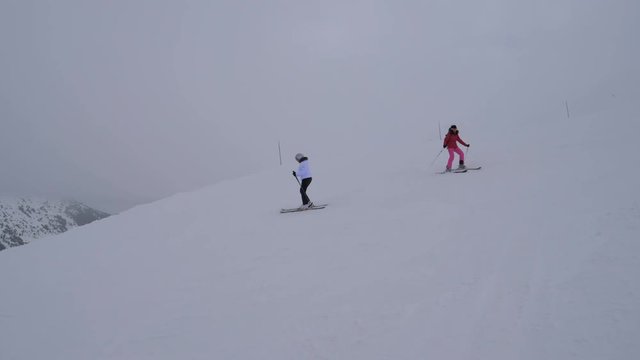 Two Sporty Female Skiers Skiing On The Mountain Downhill In Winter Holidays