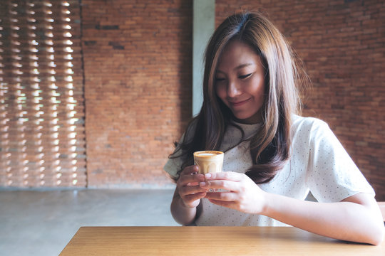 Closeup image of an Asian woman holding a coffee cup before drinking with feeling good in cafe
