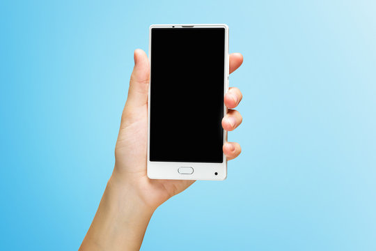 Mockup of female hand holding white frameless cell phone with black screen isolated at blue background.