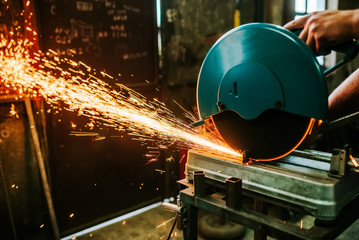 Sparks flying while cutting metal with mitre saw. - obrazy, fototapety, plakaty