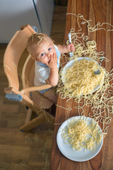 Little baby boy, toddler child, eating spaghetti for lunch and making a mess