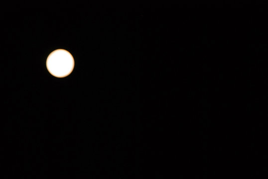 Vollmond 
Ein milchig weißer Vollmond steht am schwarzen Nachthimmel.
