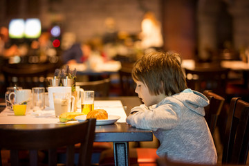Little boy, child, enjoying breakfast in hotel restaurant