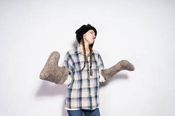 the dissatisfied Russian girl with pigtails, in a warm fur hat waits for the winter, holds gray...