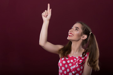 Joyful brunette girl with bright makeup, pointing up her finger. Space for text