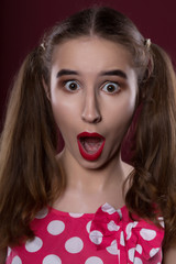 Closeup portrait of amazed brunette girl with bright makeup, posing on a red background
