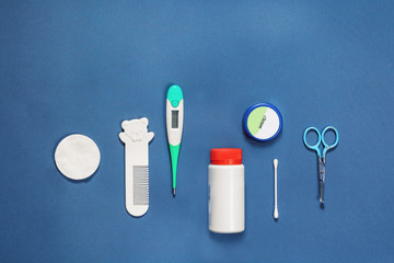 Accessory for the care of a newborn, scissors, comb, cream, powder, thermometer, stick, cotton wool, on a blue turquoise background, Flatlay