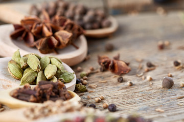 Colourful aromatic various spices for cooking on old wooden board, close-up, flat lay, selective focus, vertical.