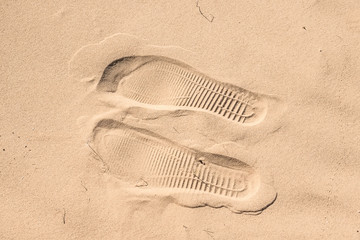 Two shoe imprints on sand in desert