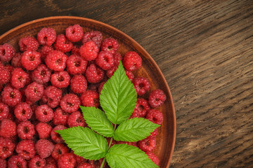 A bunch of red raspberries in a big plate. Diagonal division of the frame.