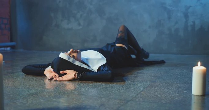Beautiful and sexy sinful nun lying on the floor and posing