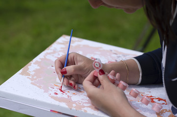 Girl enthusiastically draws a picture on canvas by numbers