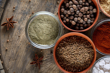 Spices in ceramic bowls on the top of wooden barrel, close-up, selective focus, vertical.