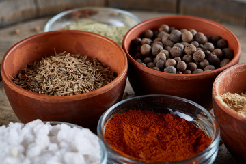 Spices in ceramic bowls on the top of wooden barrel, close-up, selective focus, vertical.