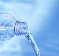 Obraz na płótnie Canvas Blue bottle pouring water against blue color background