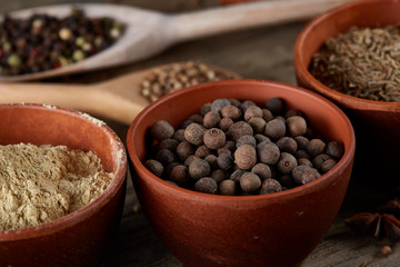 Various spices in wooden spoons and bowls and some salt on an old wooden barrel, top view, close-up, selective focus.
