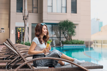 Portrait of pretty cheerful woman resting in vacation on summer season at resort swimming pool