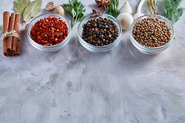 Clay bowls with spices arranged in rows with other herbs on white textured background, view from above.