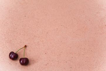 Two raw sweet cherries isolated on a plywood background  with a copy space for text
